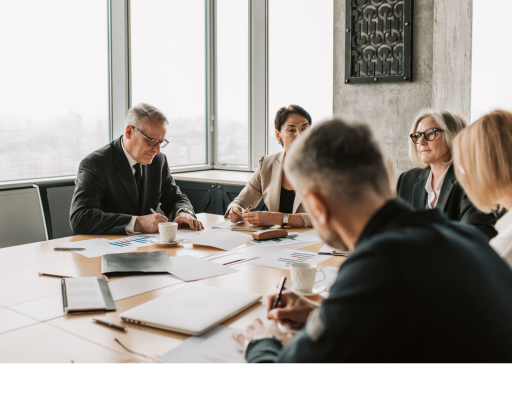 Grupo de executivos em uma reunião corporativa, com documentos e gráficos sobre a mesa. banner imagem